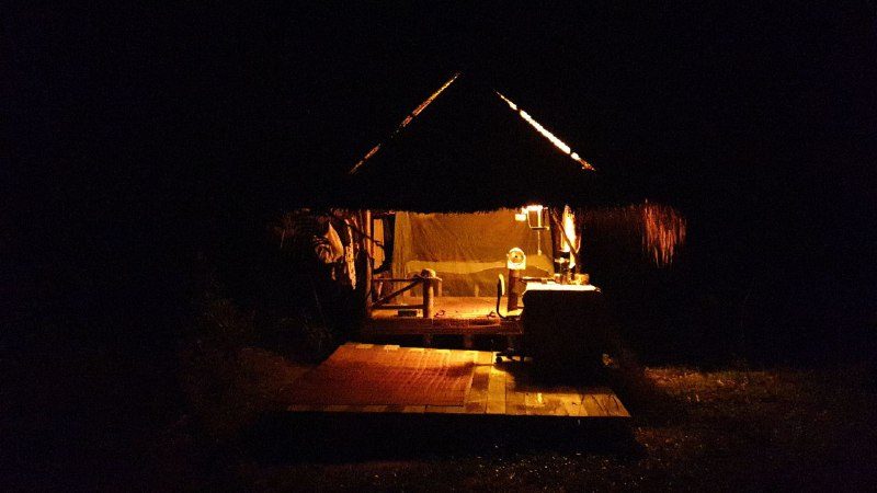 The hut lit up at night, surrounded by darkness